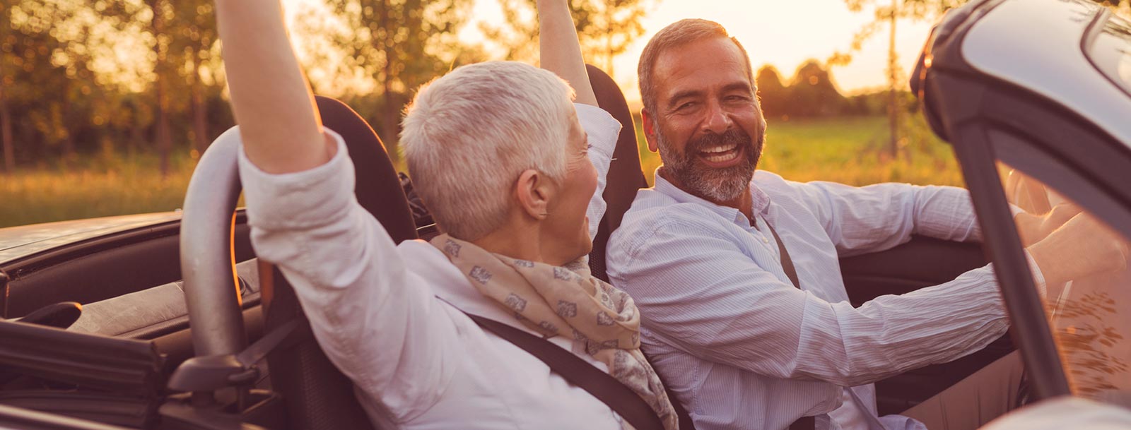 Mature couple riding in a convertible.