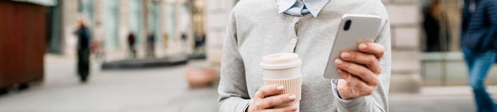 Woman with phone and coffee outdoors.