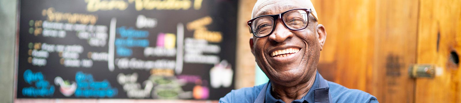 Man smiling wearing apron at cafe.